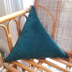 a green pillow sitting on top of a wooden chair next to a wicker radiator