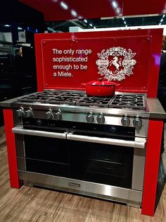 a stainless steel stove and oven on display at a trade show in an area with wood flooring