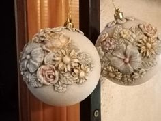 two ornaments hanging from a door with flowers on them, one is white and the other is pink