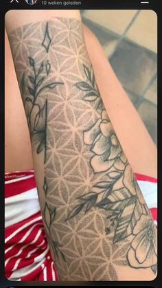 a woman's arm with flowers and leaves tattooed on the side of her leg