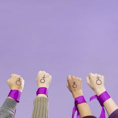 four people are holding their hands up in the air with symbols drawn on them,