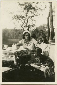 an old black and white photo of a woman sitting at a table with her cat