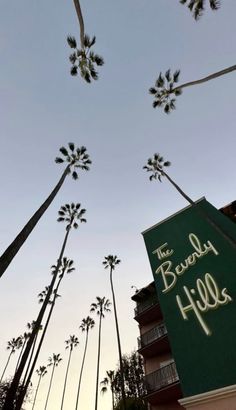 palm trees in front of a hotel sign and building with the words the beverly hills written on it