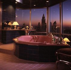 a bathroom with a large jacuzzi tub overlooking the city at sunset or dawn