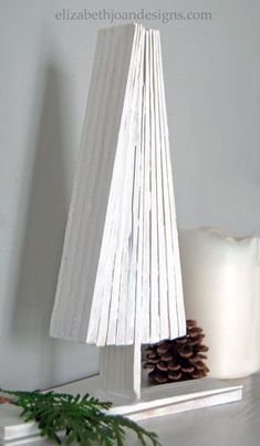 a small white christmas tree on top of a table next to a candle and some pine cones