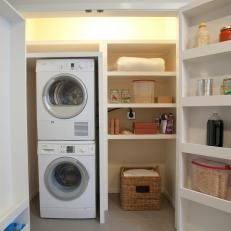 a washer and dryer sitting in a room next to shelves with items on them