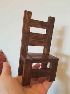 a hand holding a wooden chair made out of wood