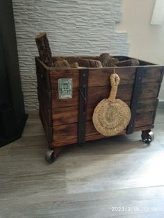 an old wooden crate with rope and wood handles is sitting on the floor in front of a brick wall