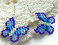 two blue and white beaded earrings sitting on top of a blanket