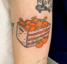 a tattoo with oranges in a wooden crate