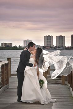 a bride and groom kissing on a pier