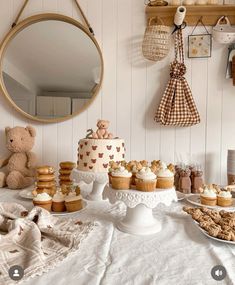 a table topped with lots of cakes and cupcakes next to a teddy bear