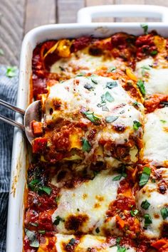 a casserole dish with meat, cheese and tomato sauce on the bottom is being lifted by a spatula