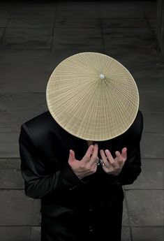 a person with a hat on their head and hands in front of them, covering his face