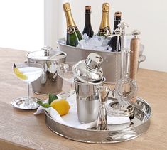 an assortment of silverware and champagne on a table with ice buckets, lemon wedges, and wine glasses