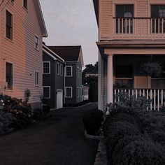 an empty street in front of two houses at dusk with the sun setting on the other side