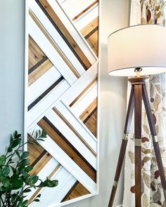 a lamp sitting on top of a wooden table next to a wall mounted art piece