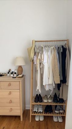 an organized closet with shoes and clothes hanging on racks, next to a dresser in a bedroom