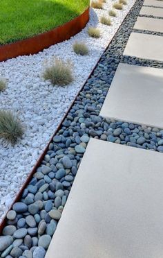 a garden with rocks and grass in the middle, along side a path that leads to a grassy area