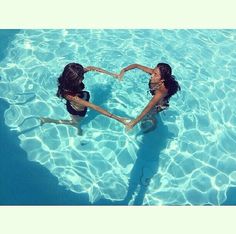 two girls in the water making a heart shape with their hands