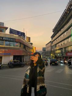 a woman taking a selfie in the middle of a busy city street at sunset