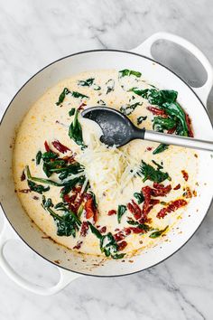 a pot filled with cheese and spinach on top of a white marble countertop