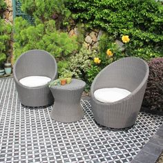 two wicker chairs sitting on top of a black and white tile floor next to plants