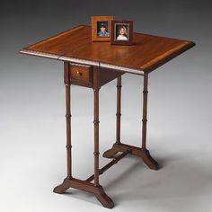 a small wooden table with two pictures on it's top and one drawer at the bottom