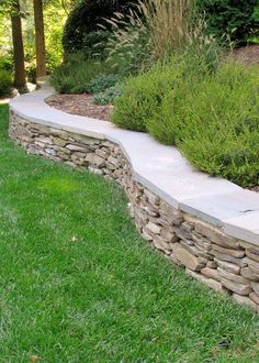 a stone wall in the middle of a grassy area