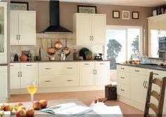 a kitchen filled with lots of white cabinets and counter top space next to a dining room table