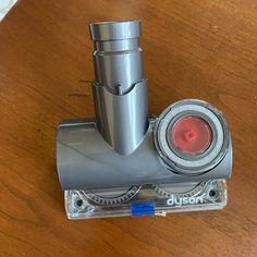 a metal object sitting on top of a wooden table next to a glass holder with a red light in it