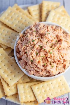 a bowl filled with tuna and crackers on top of a white plate next to some crackers