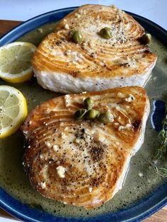 two pieces of fish on a plate with lemons