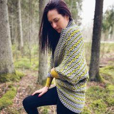 a woman is standing in the woods wearing a crocheted sweater and leggings