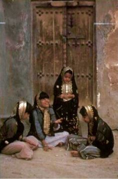 three women kneeling down in front of a door with their hands on the ground and one holding a cup