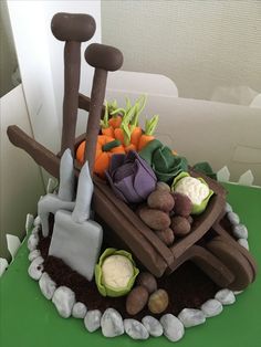 a cake made to look like a wheelbarrow with vegetables and gardening tools on top