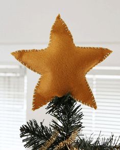 a felt star ornament hanging from a christmas tree with the words diy felt tree topper