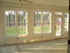 an empty room with three windows and a ceiling fan