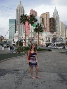 a woman standing in the middle of an empty street with palm trees and buildings behind her