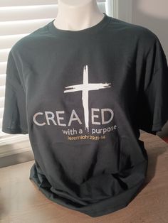 a black t - shirt with the words created with purpose on it and a cross