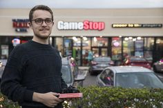 a man standing in front of a game stop holding a camera