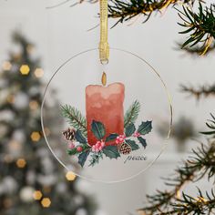 a christmas ornament hanging from a tree with a candle and pine cones on it