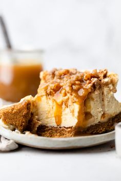 a piece of cheesecake on a white plate with caramel sauce in the background