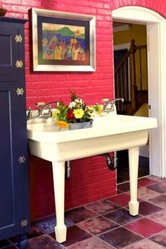 a red brick wall with a white table and blue cabinets in the corner next to it