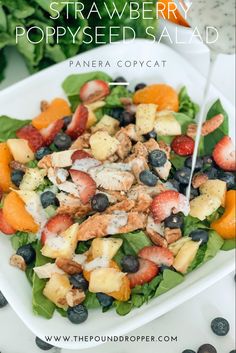 a white plate topped with fruit salad next to lettuce and strawberries on top