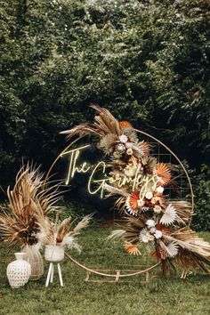 an image of a wedding arch with flowers and feathers on the grass in front of trees