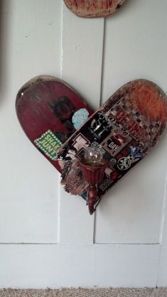 a skateboard hanging from the side of a white wall next to a hook with stickers on it