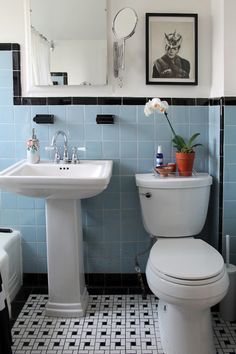 a white toilet sitting next to a sink in a bathroom under a framed picture on the wall