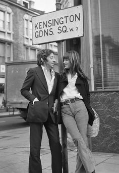 a man and woman standing next to a street sign