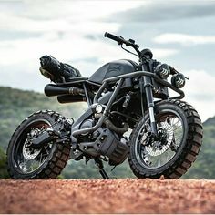 a black motorcycle parked on top of a dirt road